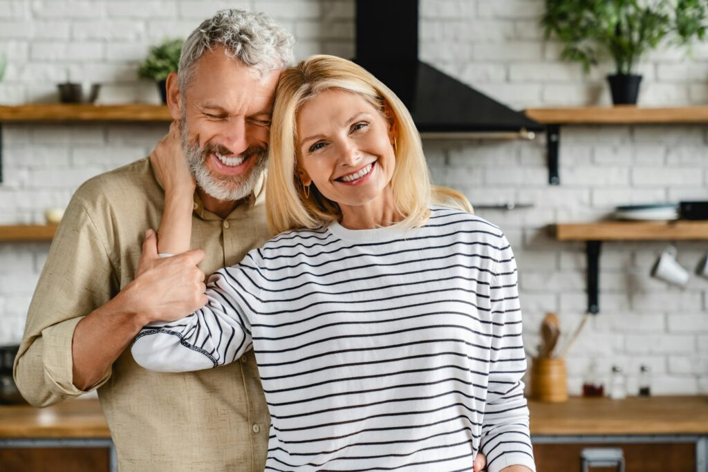 Happy middle aged couple embracing at home kitchen