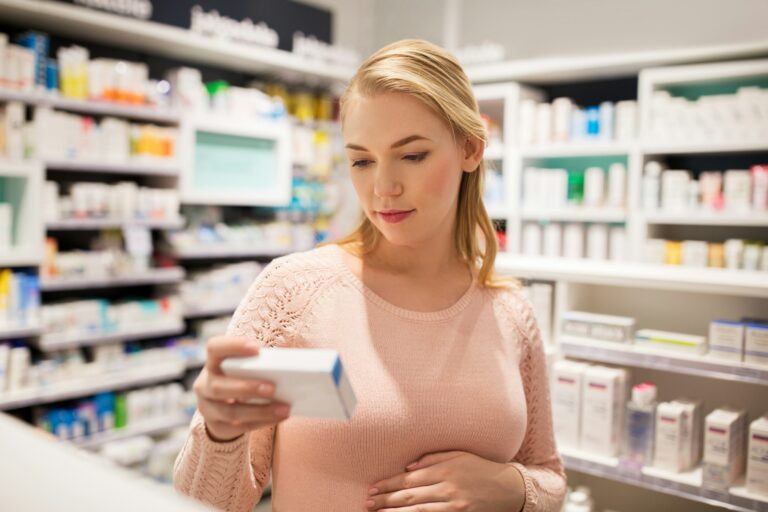 happy pregnant woman with medication at pharmacy